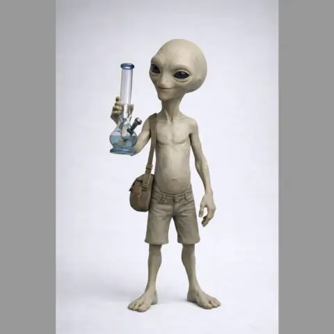 Alien figure with large eyes holding a glass object, wearing shorts and a bag over shoulder.
