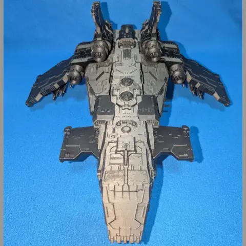 Futuristic armored spaceship model with wings, detailed surface, and compartments, set on a blue background.