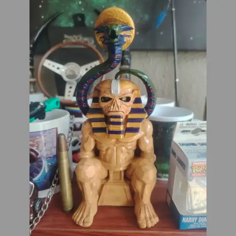 A statue of a muscular, mummy-like figure with an Egyptian pharaoh headdress, serpent, and ankh.