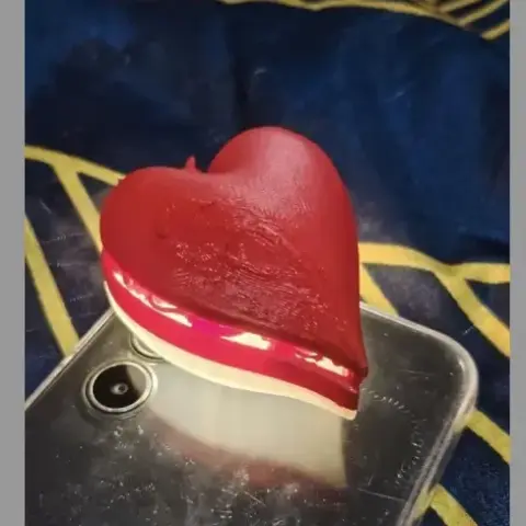 3D-printed red heart with visible layers, placed on a smartphone.