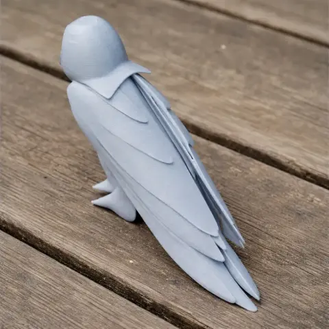 3D-printed gray barn owl model with detailed wings, perched on wooden surface.