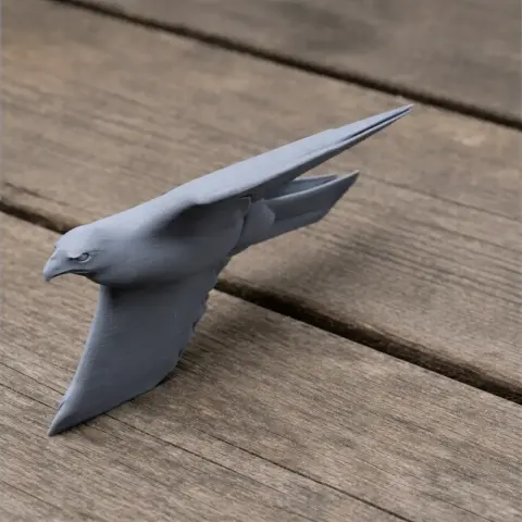 A 3D-printed model of a booted eagle in mid-flight, displayed on a wooden surface.