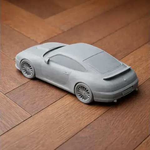 A detailed 3D-printed model of a sleek sports car, placed on a wooden floor.