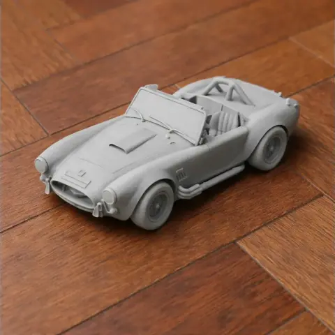 3D printed scale model of an AC Cobra car with detailed interior and exterior on a wooden surface.