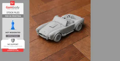 Gray 3D printed model of an AC Cobra car on a wooden surface.