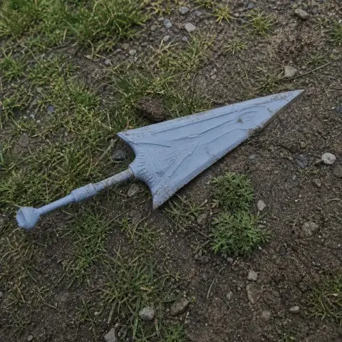 A 3D-printed, ornate fantasy sword prop with a triangular blade and intricate hilt, lying on grassy soil.