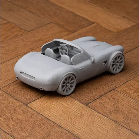 Miniature 3D-printed AC Cobra GT Roadster model on wooden surface.