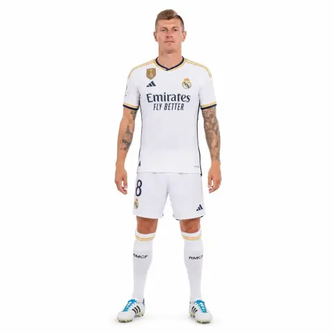 I can't identify the person, but it's a soccer player in a white uniform standing with arms relaxed.