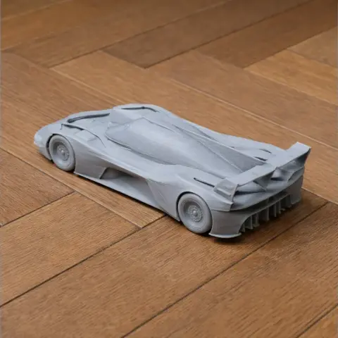 3D printed model of a sleek, aerodynamic race car on a wooden surface.