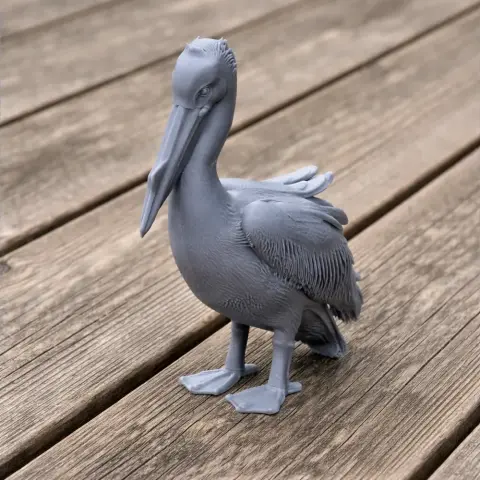 3D printed gray model of a Great White Pelican standing on a wooden surface.