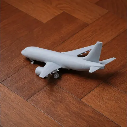 3D printed model of an Airbus A220 airplane on a wooden floor.