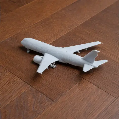 A small 3D printed white model of an Airbus A350 airplane on a wooden surface.