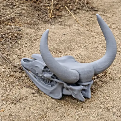 3D-printed aurochs skull model with large curved horns on a sandy surface.