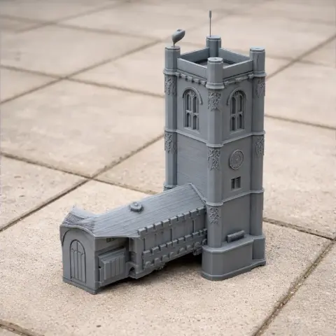 Miniature gray architectural model with a tall, detailed tower and adjoining building on tiled ground.