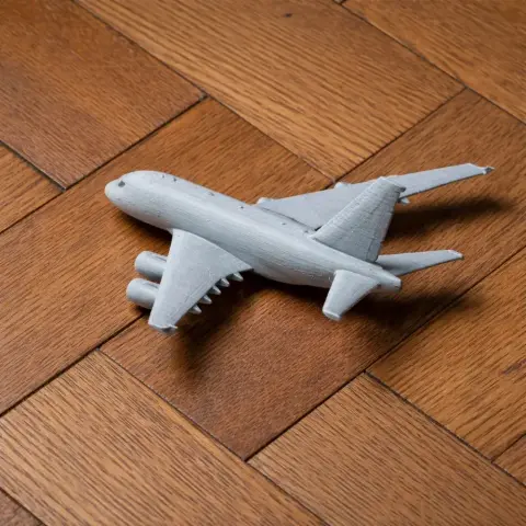 3D-printed model of an Airbus A380 displayed on a wooden surface.