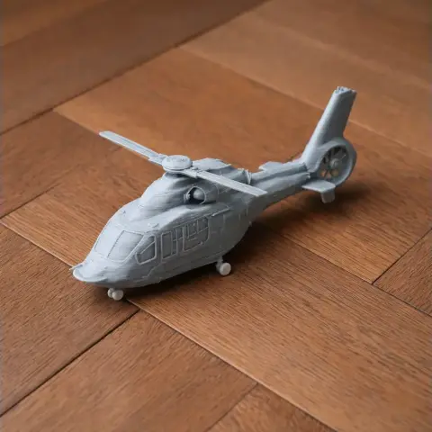 3D-printed model of an Airbus H160 helicopter on a wooden surface.