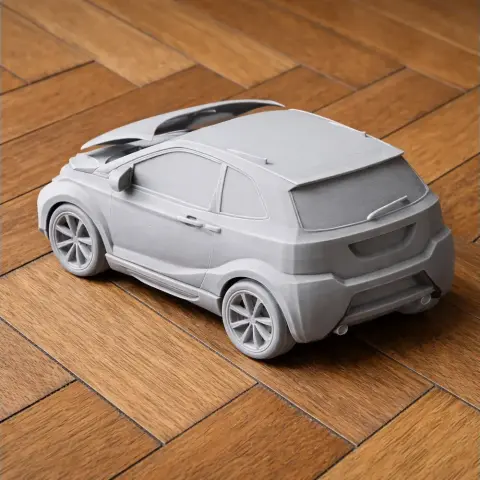 A 3D-printed, unpainted scale model of a compact vehicle on a wooden surface.