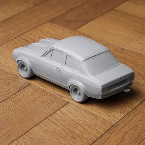 A 3D-printed scale model of a classic racing car on a wooden surface.