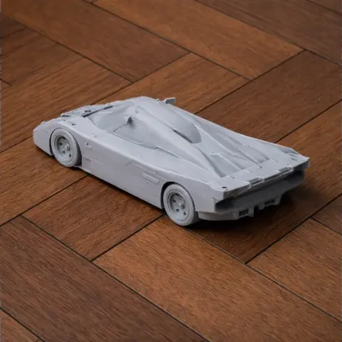 3D printed scale model of a sleek, futuristic car on a wooden floor.