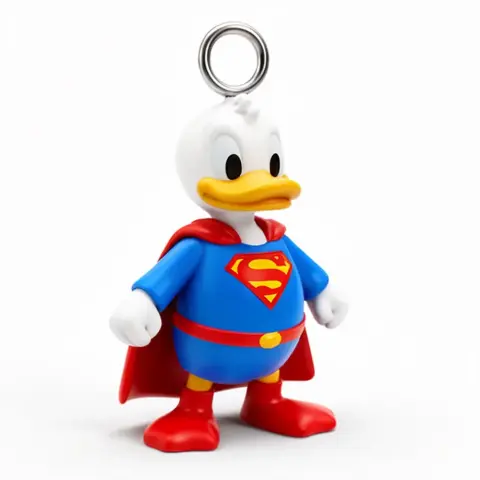 Duck figure dressed as Superman with a red cape and “S” emblem, wearing a small ring on top.