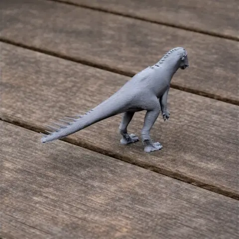 Gray 3D-printed model of a dinosaur-like creature with a long tail and spikes on its back.