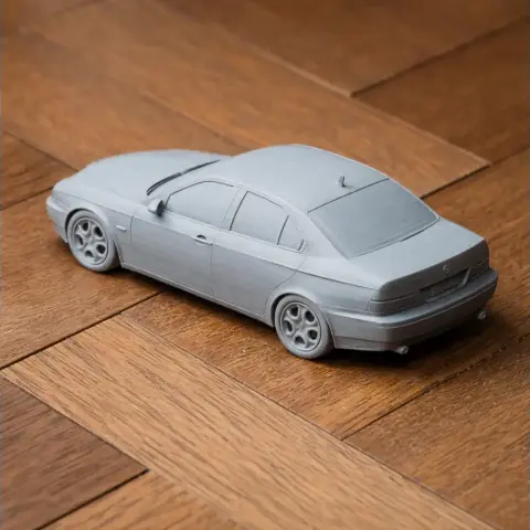 3D printed model of a grey Alfa Romeo 156 car on a wooden surface.
