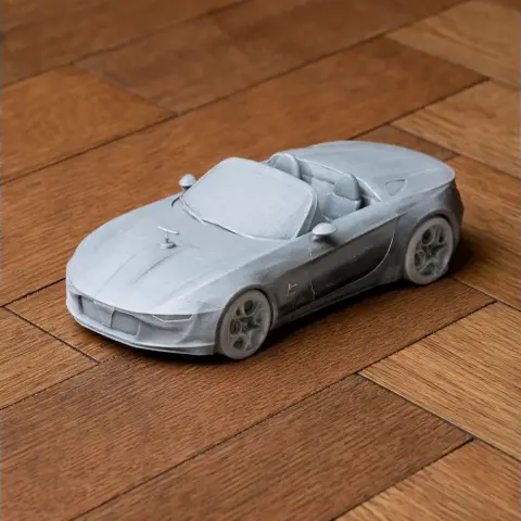3D-printed model of a sleek Alfa Romeo convertible car on a wooden surface.
