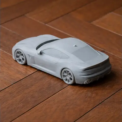 Gray 3D printed model of an Alfa Romeo 6C car on a wooden surface.
