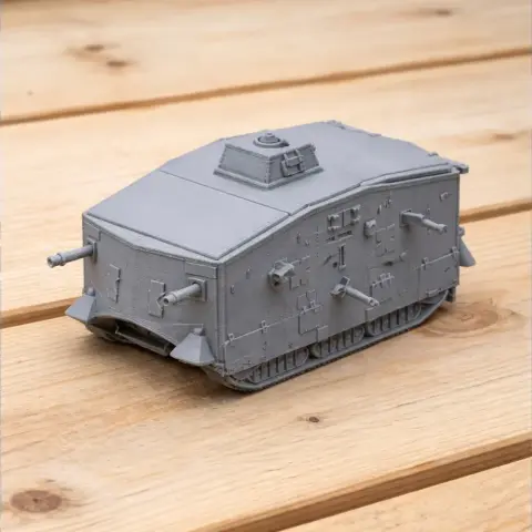 A detailed 3D-printed model of a World War I A7V tank on a wooden surface.
