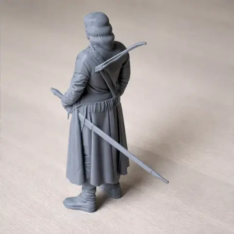 A detailed 3D-printed figurine of a cloaked character holding a sword, viewed from behind.