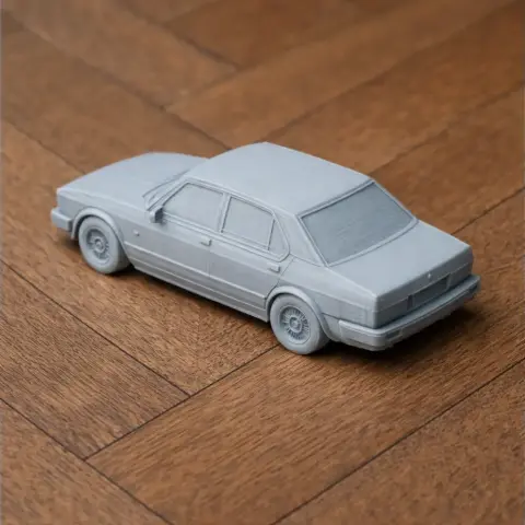 Gray 3D printed model of an Alfa Romeo Alfetta car, displayed on a wooden surface.