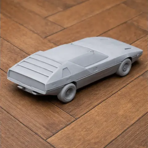 3D-printed Alfa Romeo Caimano model on a wooden surface, showcasing sleek lines and angular design.
