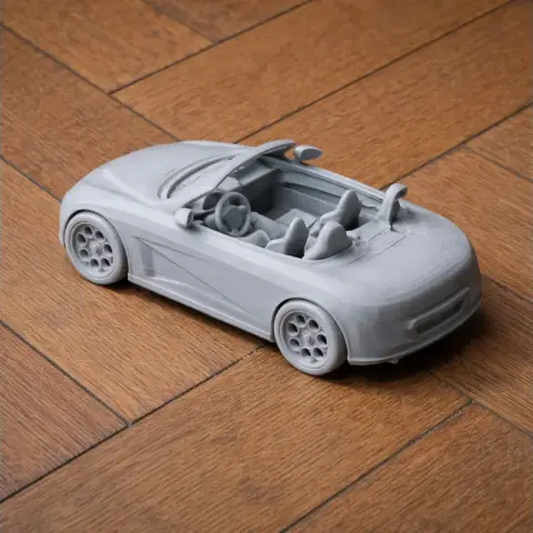 3D printed model of a convertible car with detailed interior, on a wooden floor.