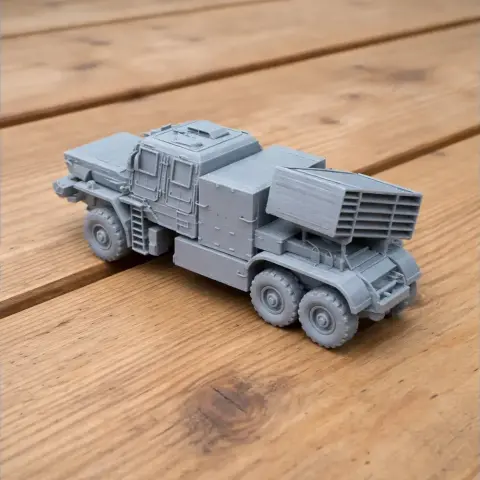 Gray 3D-printed tank model with six wheels and a missile launcher on a wooden surface.
