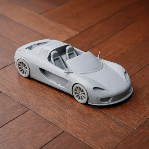 A detailed 3D-printed model of a sleek sports car on a wooden surface.