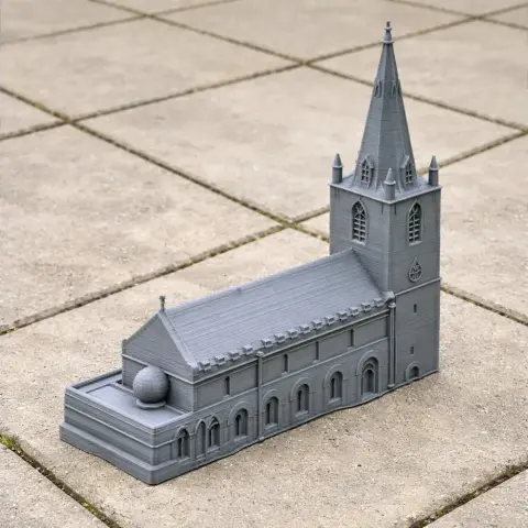 3D printed model of an Anglo-Saxon church with a tall spire on a tiled surface.