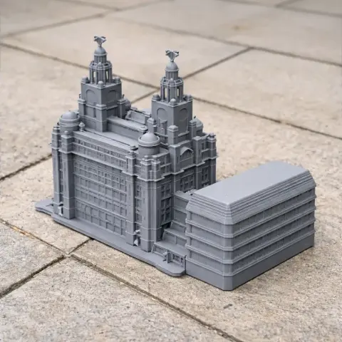 Gray 3D printed model of a detailed two-towered building with nearby modern structure.