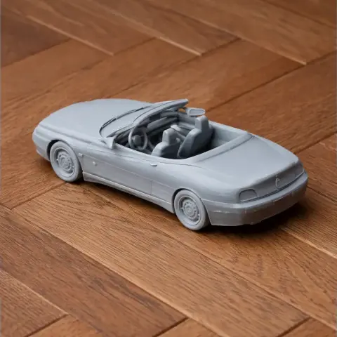 A detailed 3D printed model of an Alfa Romeo convertible car on a wooden surface.