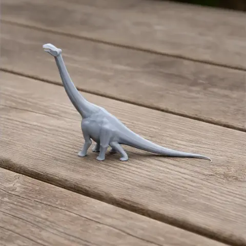 Gray 3D-printed model of a Nigersaurus dinosaur with a long neck and tail on a wooden surface.