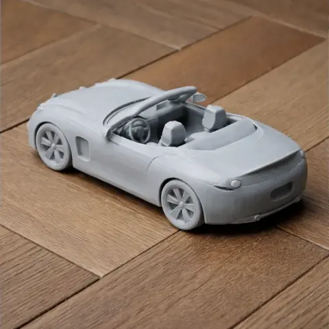 3D printed model of a convertible sports car on a wooden surface.
