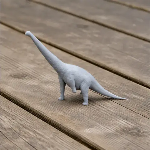 3D printed model of a long-necked dinosaur on a wooden surface.
