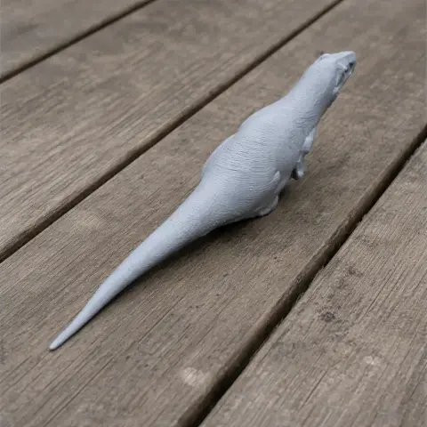 Gray 3D-printed Nototyrannus model on wooden boards, showing long tail and detailed texture.