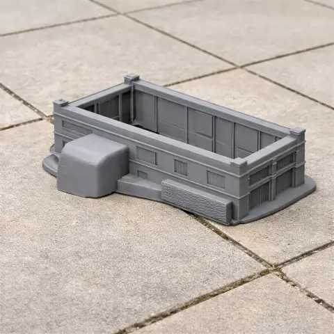 A 3D-printed gray model of a rectangular castle structure with detailed walls, placed on tiled ground.