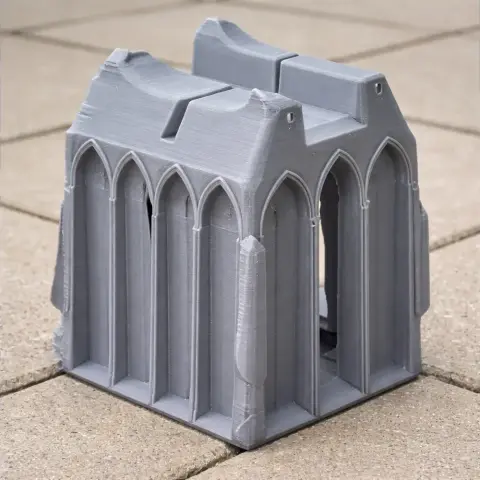 Gray 3D-printed model of a castle section with pointed arches and towers, on a tiled surface.