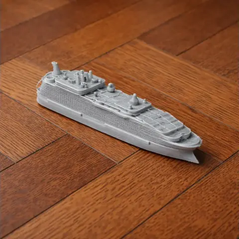3D-printed model of a cruise ship on a wooden surface.