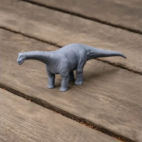 Gray 3D printed model of Opisthocoelicaudia dinosaur on wooden surface.