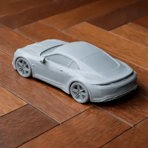 Gray 3D-printed scale model of an Alpine A110 sports car on a wooden surface.