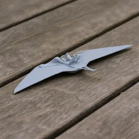 A 3D printed model of a flying Ornithocheirus with outstretched wings on a wooden surface.