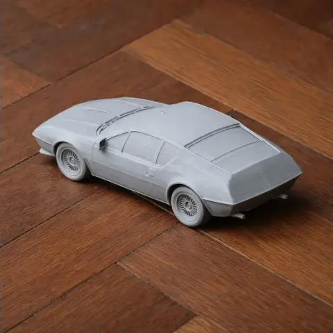 3D printed model of a gray Alpine A310 car on a wooden surface.