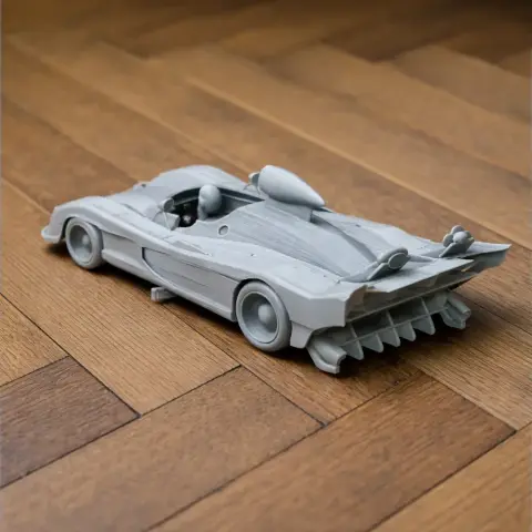 Gray 3D-printed Alpine A441 model car on a wooden surface, displayed at an angle.